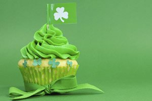 Cupcake com cobertura verde e bandeira com desenho de trevo de quatro folhas