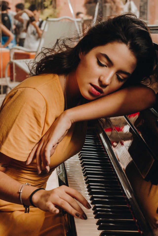 Mulher debruçada sobre um piano.