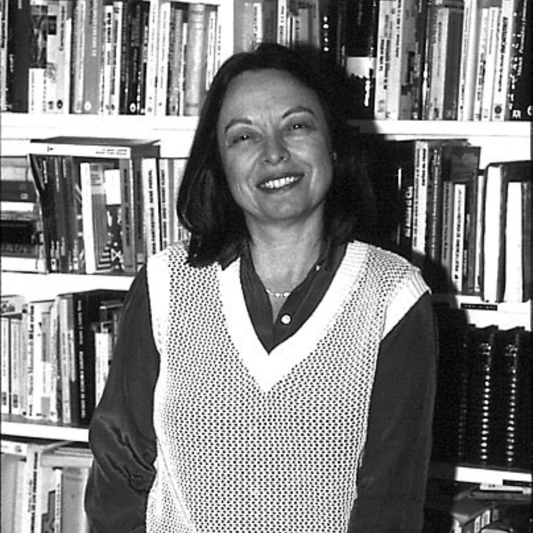 Nélida Piñon quando mais jovem, sorrindo, em frente a uma estante.