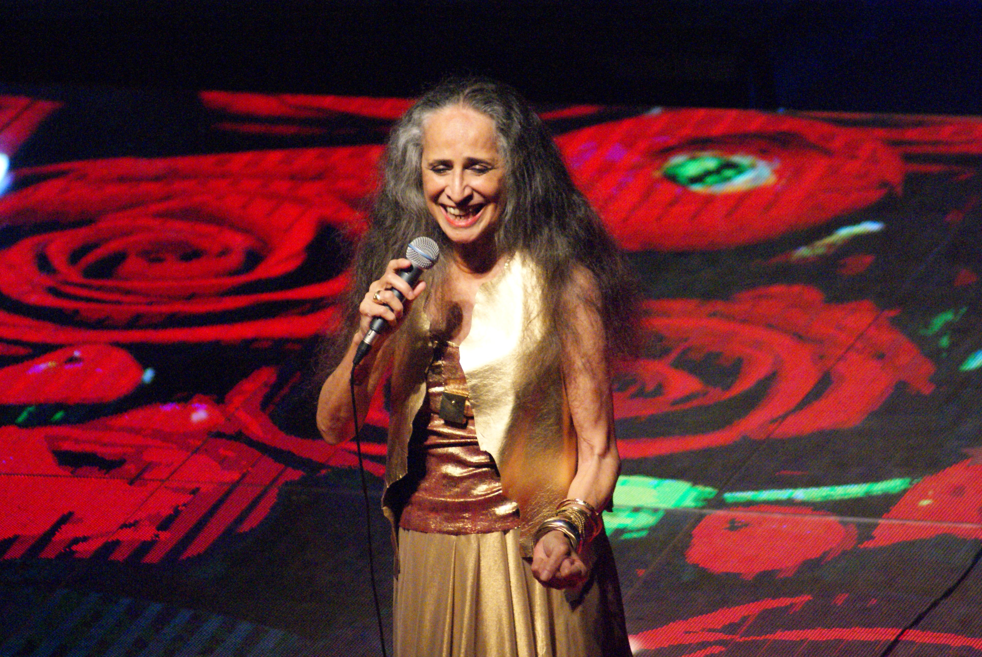 Maria Bethânia no palco cantando e sorrindo