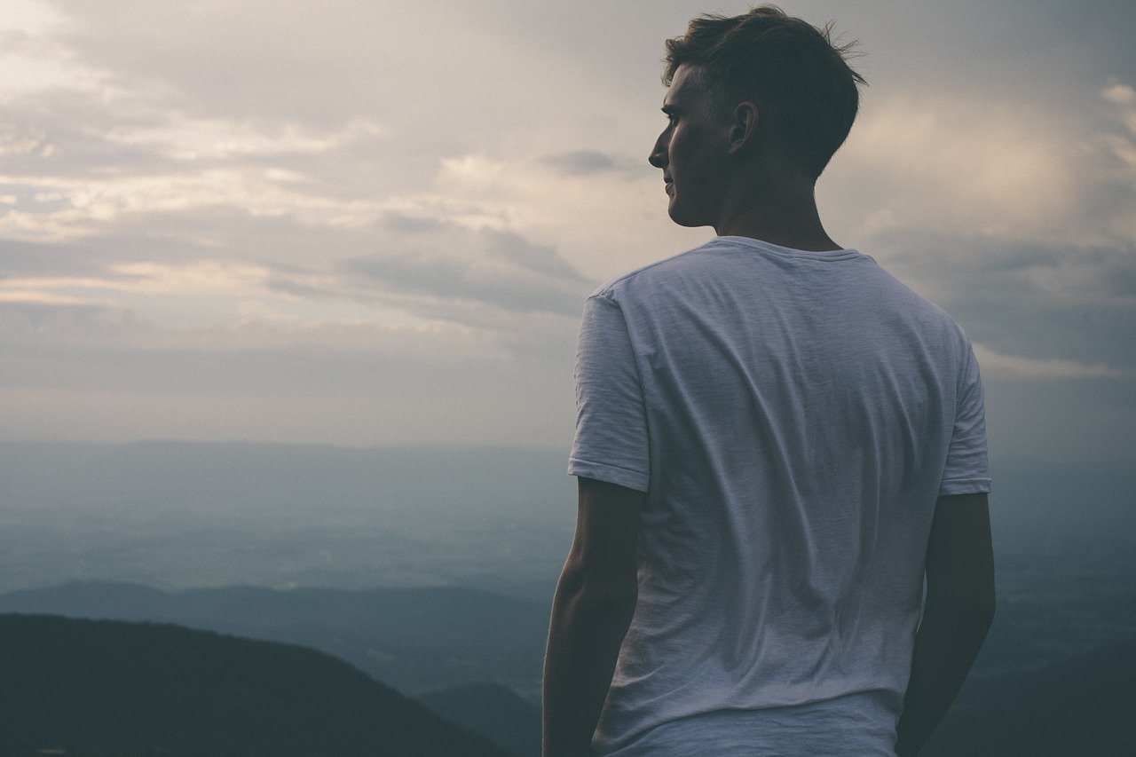 Homem olhando para o horizonte de cima da montanha