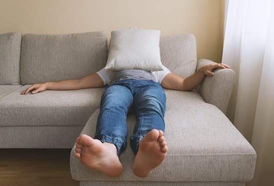 Homem deitado no sofá com almofada no rosto