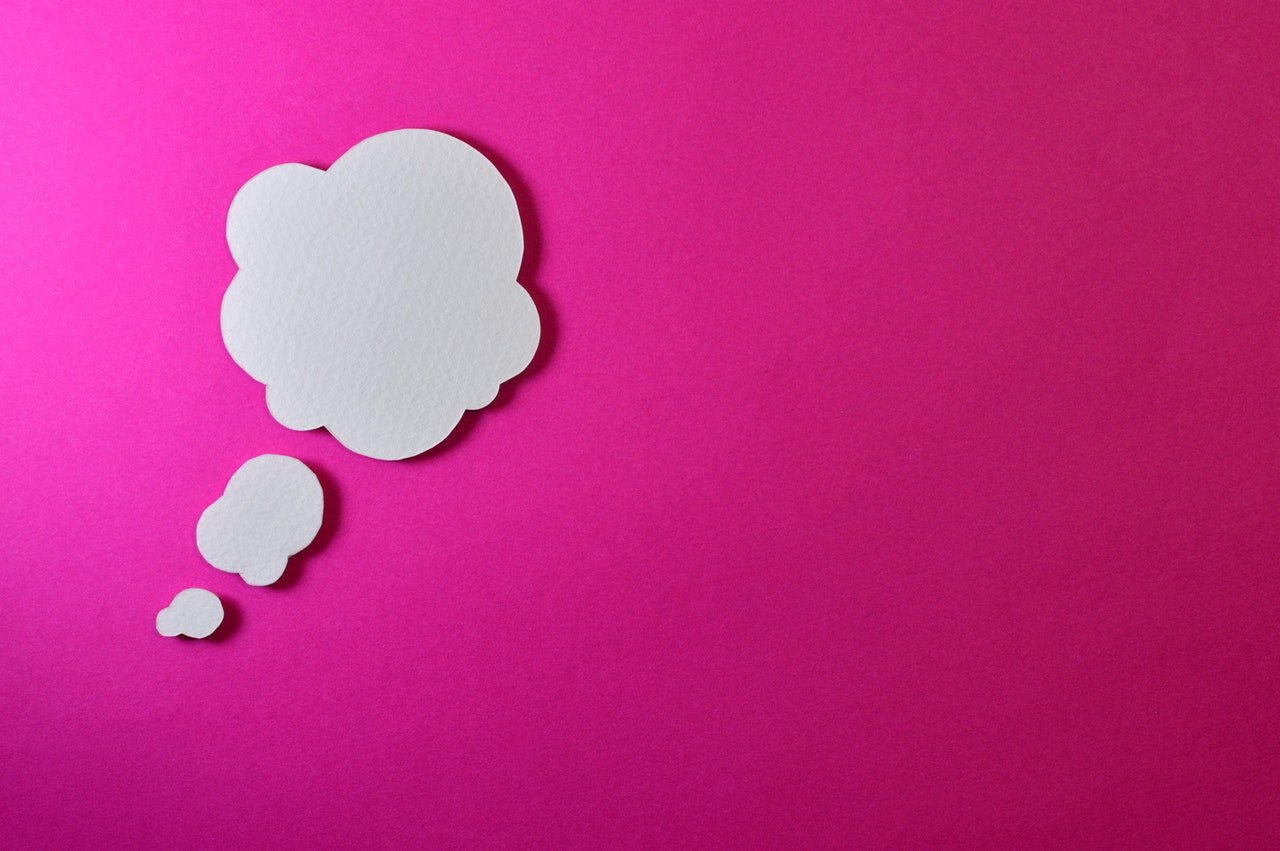 Fundo rosa, com papéis brancos recortados em formato de nuvens, que formam um balão de pensamento de quadrinhos.