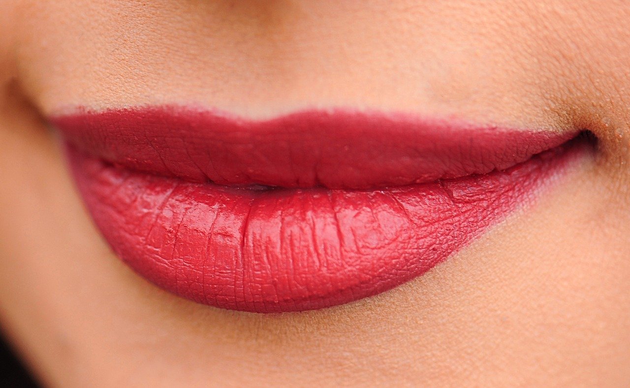Close de boca feminina com batom levemente vermelho.