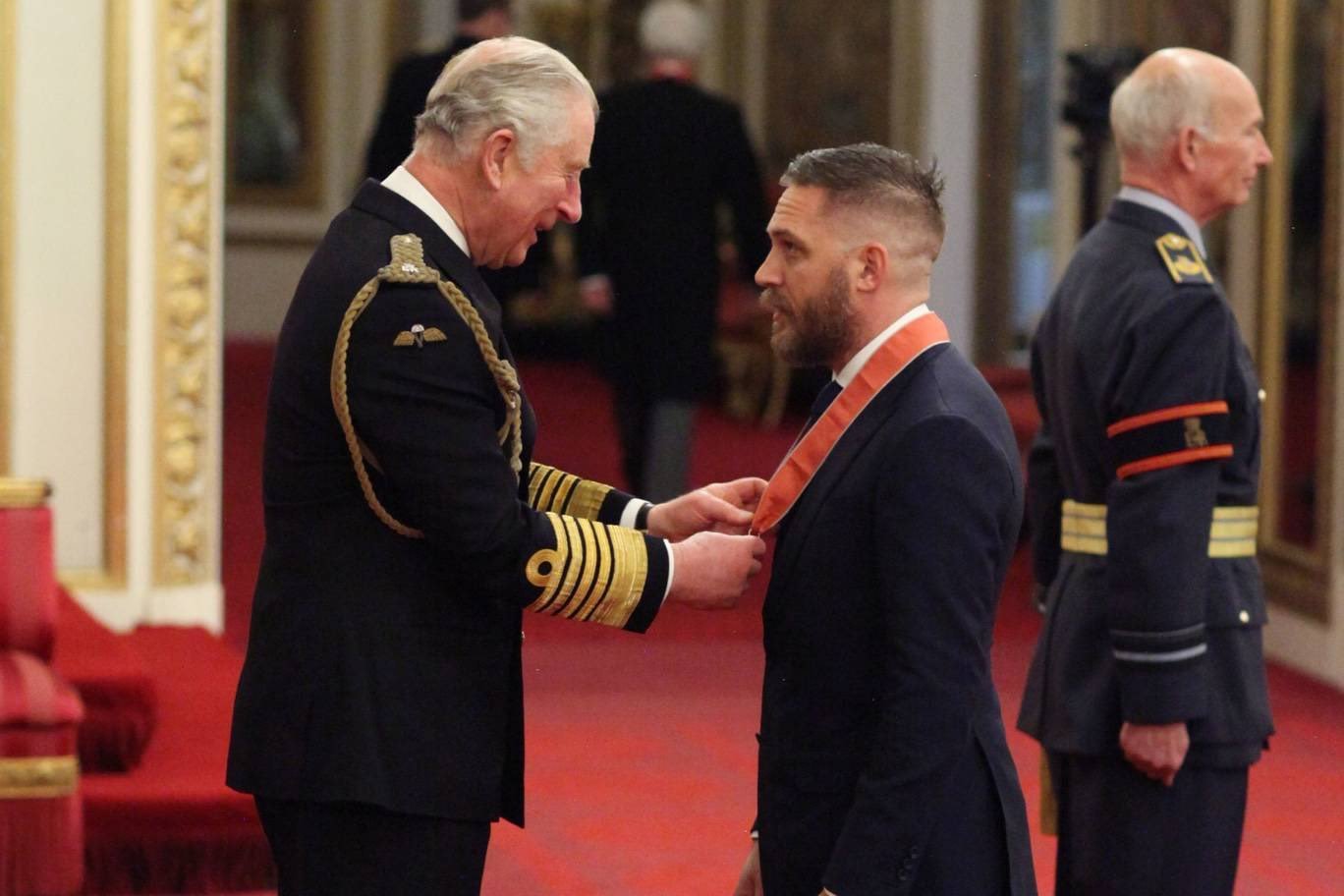 Principe Charles entregando a Tom Hardy uma medalha de Comandante do Empério Britânico.