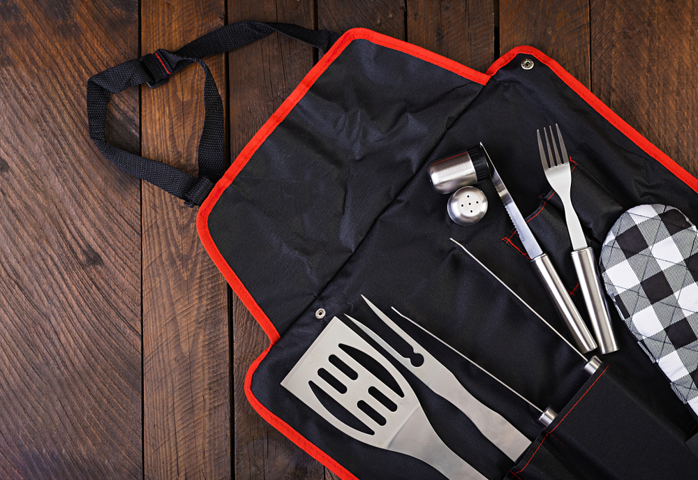 Kit de churrasco com avental, espátulas, facas, garfos, entre outros utensílios.