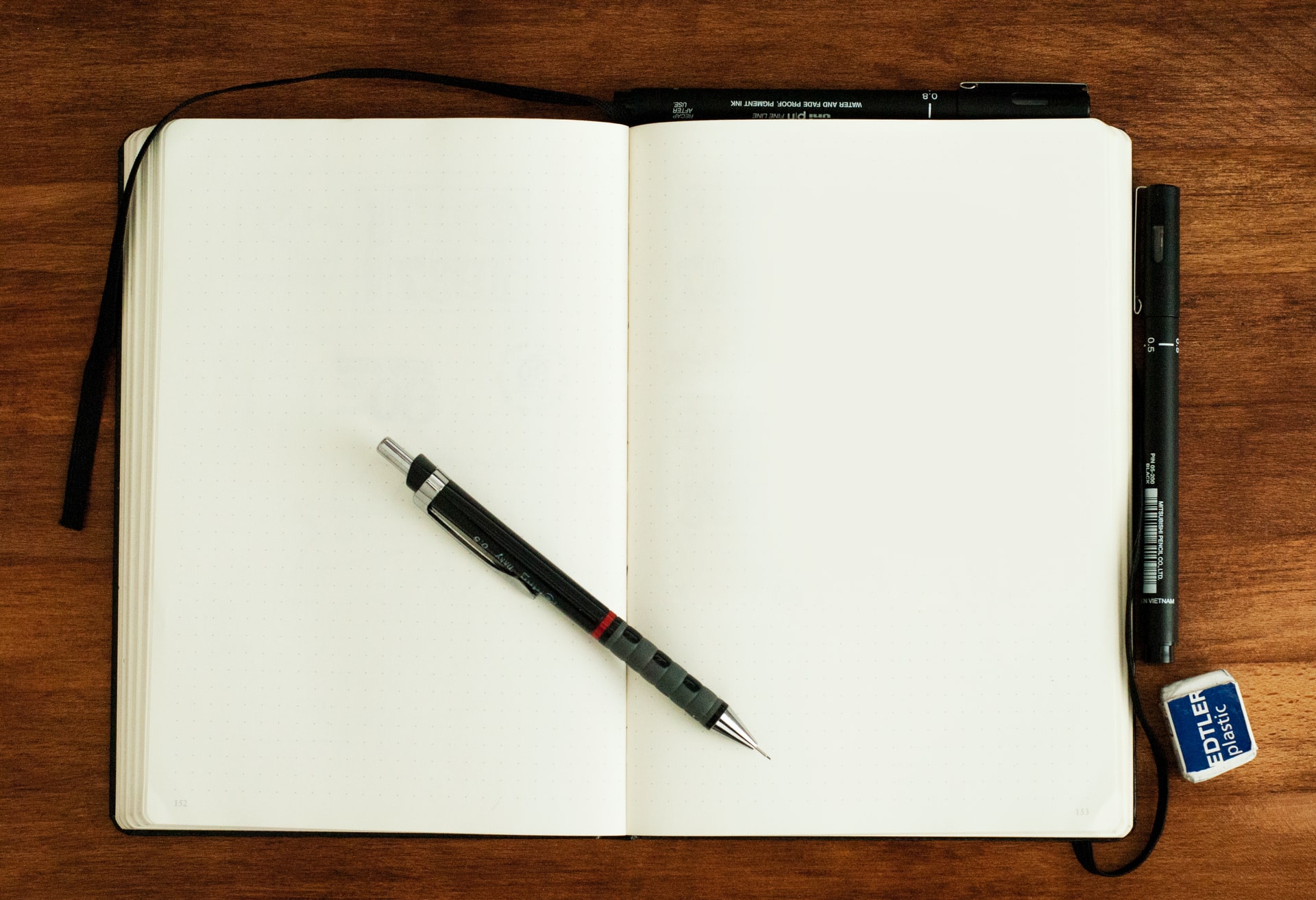 Caderno de anotações aberto com uma caneta em cima.
