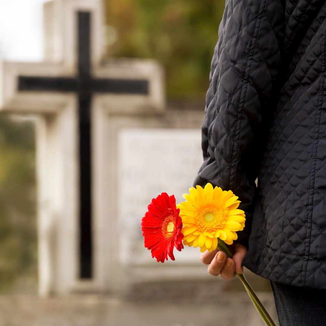 Pessoa com flores na mão perto de um túmulo