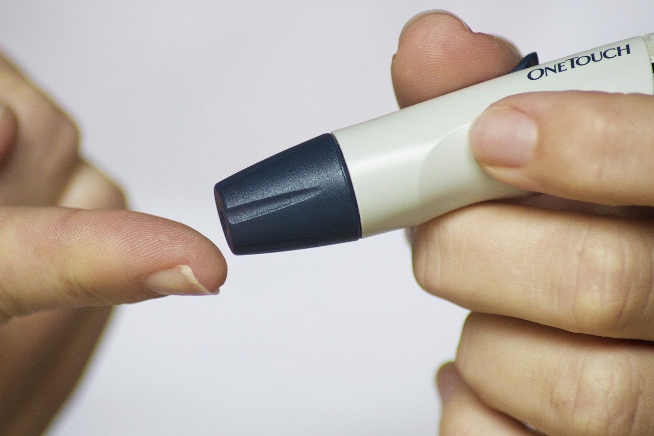 Pessoa branca medindo glicose com aparelho no dedo.
