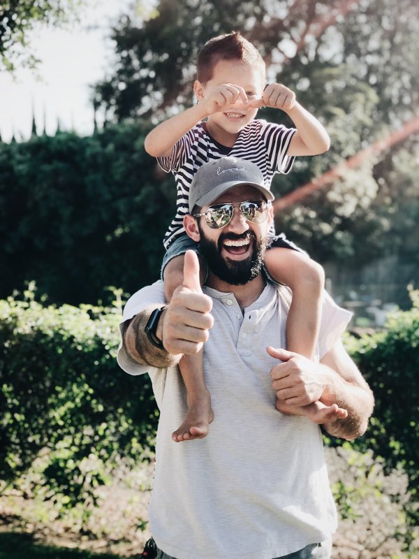 Pai com filho sentado no pescoço sorrindo