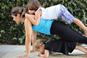 Mãe fazendo exercícios ao ar livre com seus filhos.