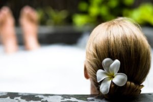 Mulher com flor no cabelo em uma jacuzzi ao ar livre.