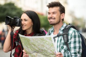 Casal de turistas com mapa e câmera fotográfica.