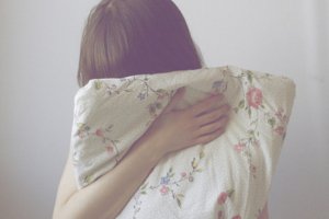 Garota segurando travesseiro em frente ao rosto