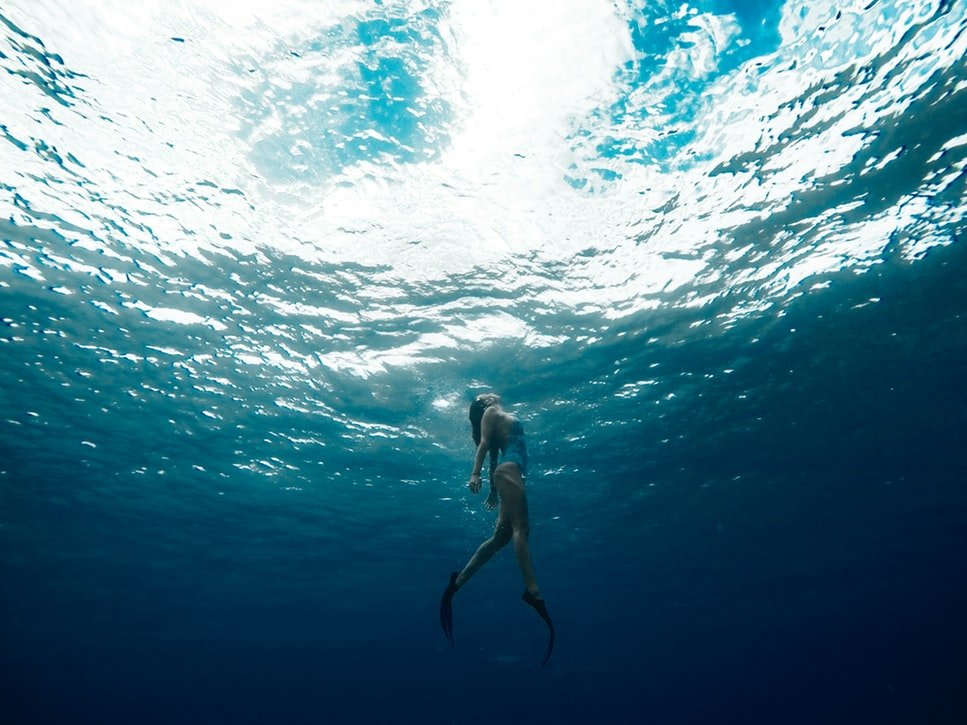 Mulher embaixo d'água, nadando com pés de pato.