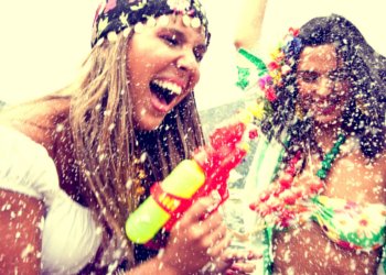 Garotas fantasiadas de carnaval sorrindo e dançando com espuma no ar