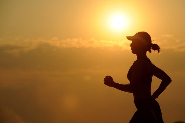 Silhueta de mulher correndo durante o nascer do sol.