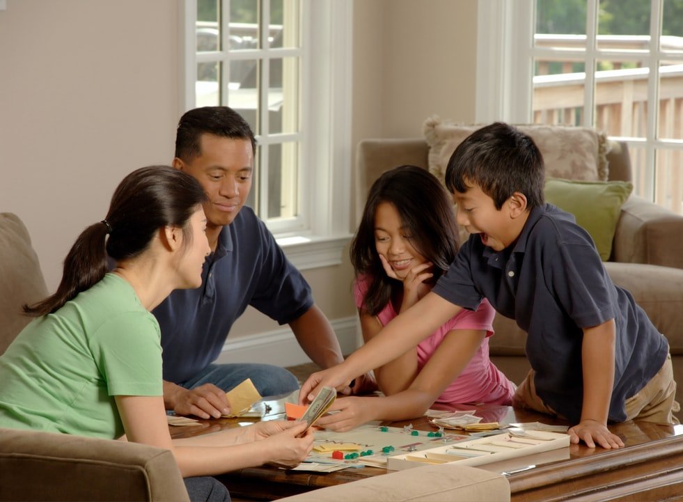 Família reunida em uma sala, jogando jogos de tabuleiro.
