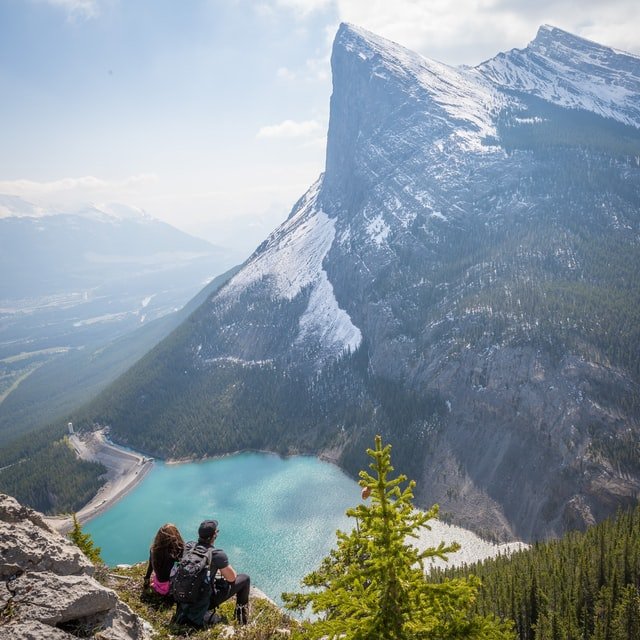 Homem e mulher sentados admirando a paisagem montanhosa
