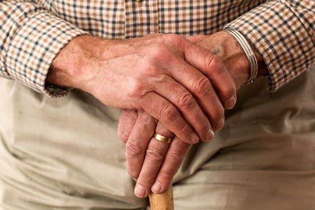 Mãos de um idoso segurando uma muleta