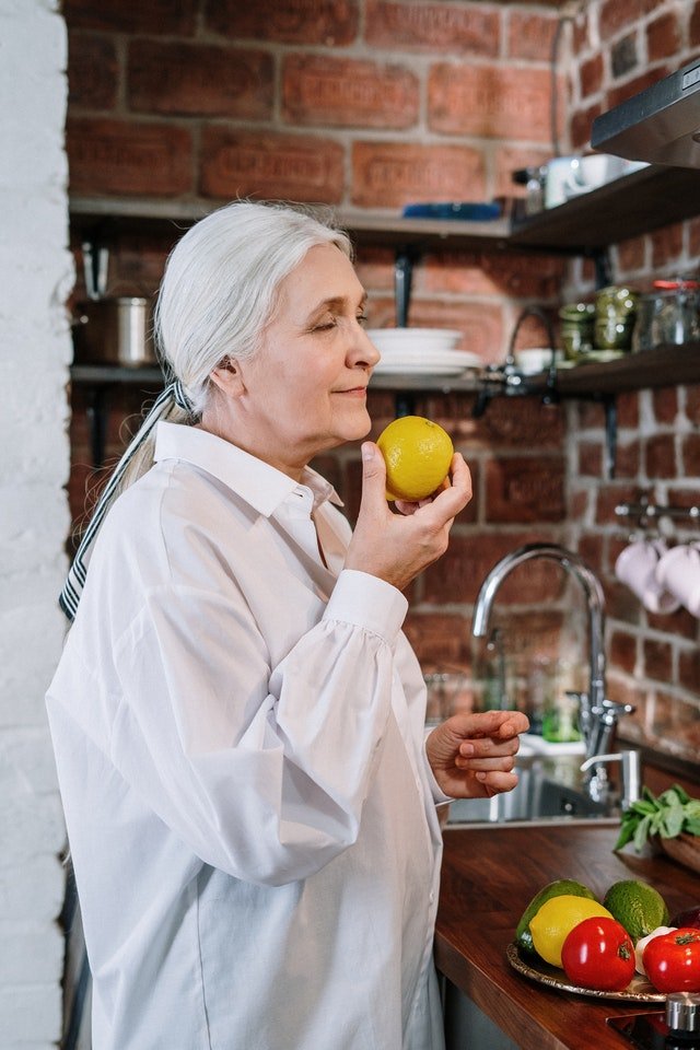 Mulher idosa comendo frutas na cozinha
