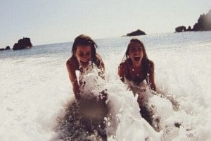 Duas amigas gargalhando no mar.