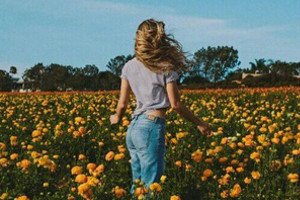 Garota com os cabelos voando em um campo de flores.