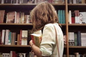 Garota em frente a uma estante de livros.