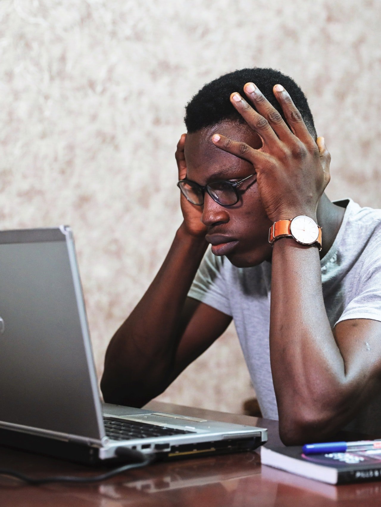 Homem trabalhando em um computador, cansado, apoiando a cabeça nas mãos.