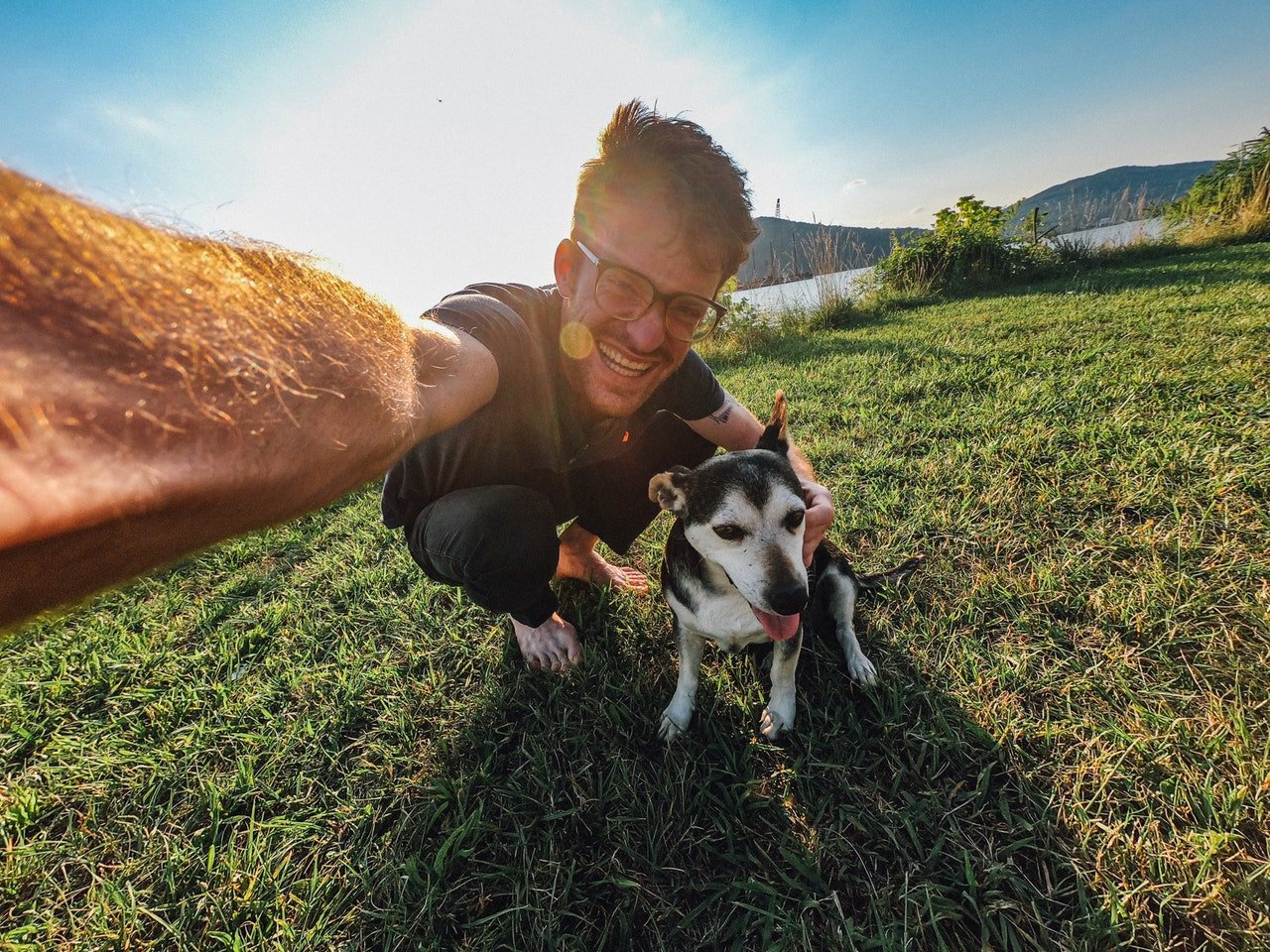 Homem sorrindo tirando selfie com um cachorro
