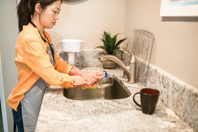 Mulher asiática lavando louça.