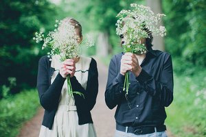 Casal segurando flores diante de seus rostos.