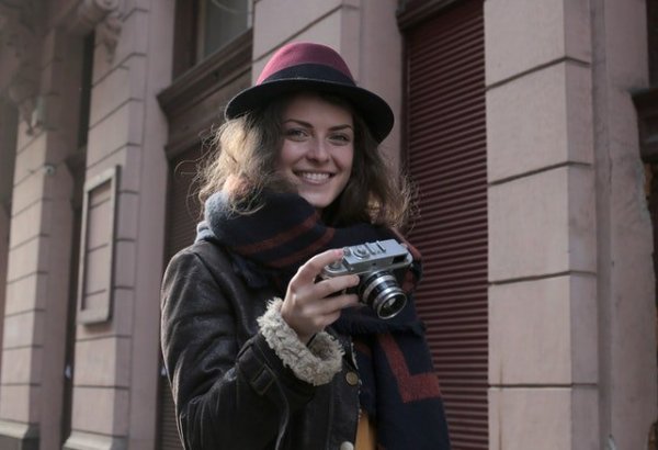 Pixels/Andrea Piacquadio Mulher sorrindo segurando câmera fotográfica.