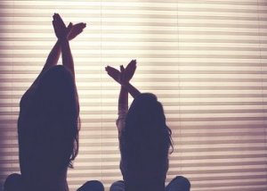 Duas meninas fazendo um pássaro com as mãos, símbolo de paz.