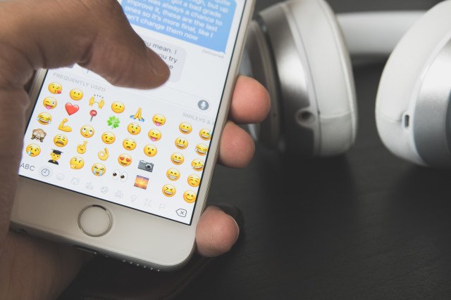 Celular ligado com teclado de emojis.