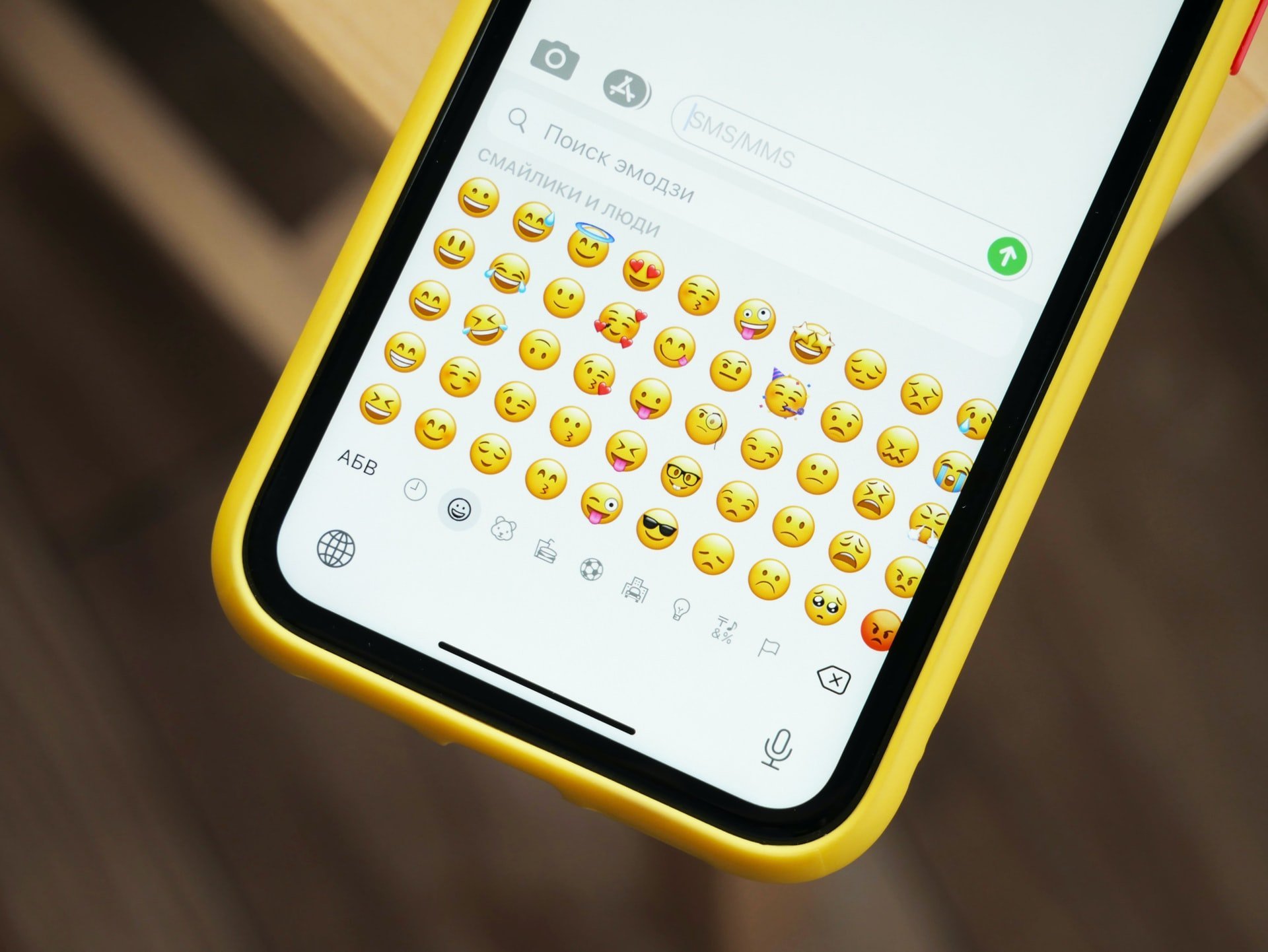 Celular ligado com emojis no teclado.