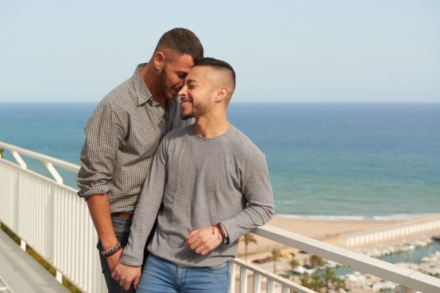 Casal gay de mãos dadas em uma ponte perto da praia