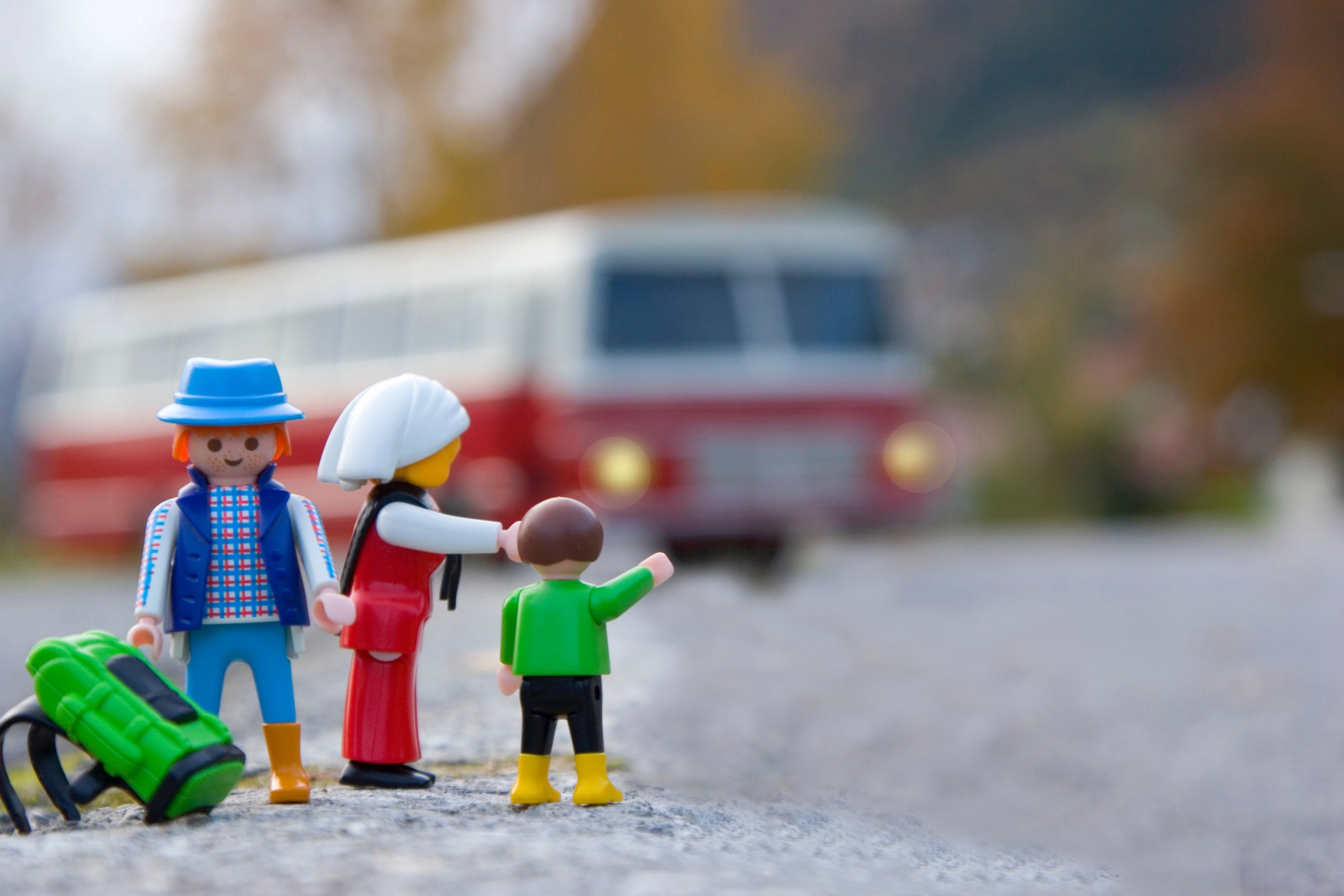 Família de bonecos e ônibus ao fundo
