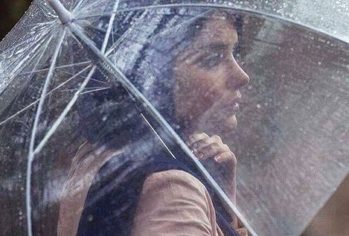 Mulher vista através de guarda-chuva transparente