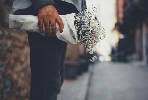 Mão de homem segurando buquê de flores
