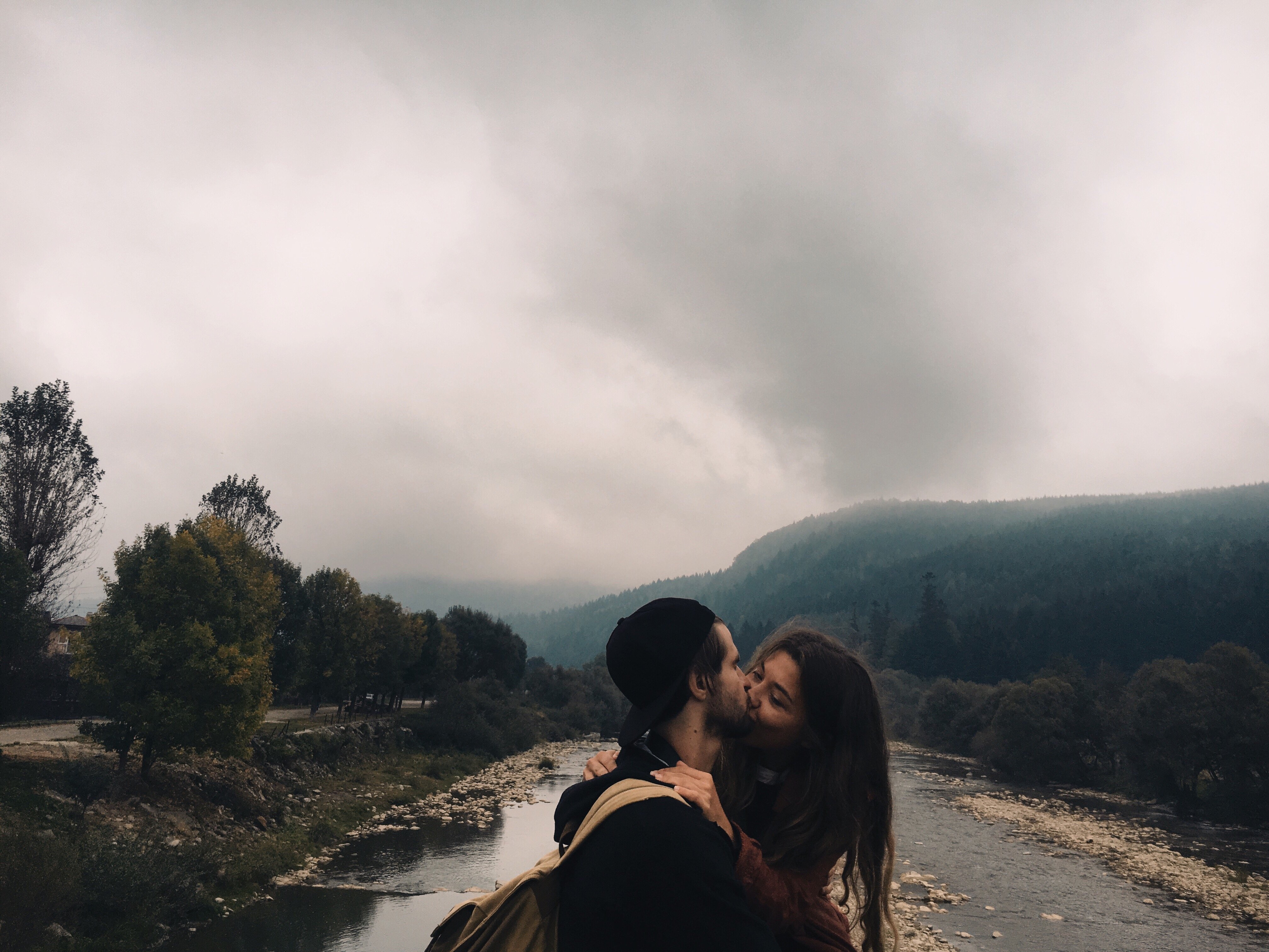 Casal se beijando ao lado de um rio