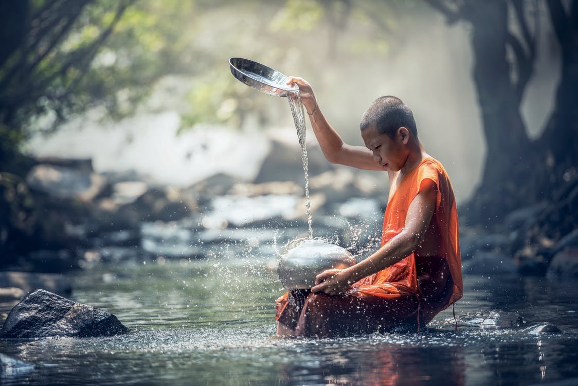 Monge jogando água em utensílio