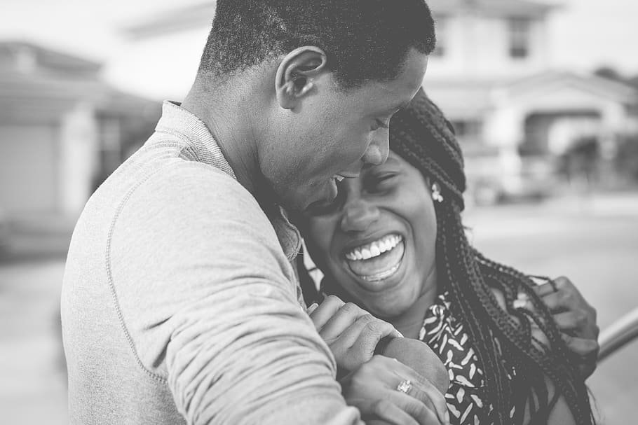 Homem e mulher se abraçando de lado enquanto riem.