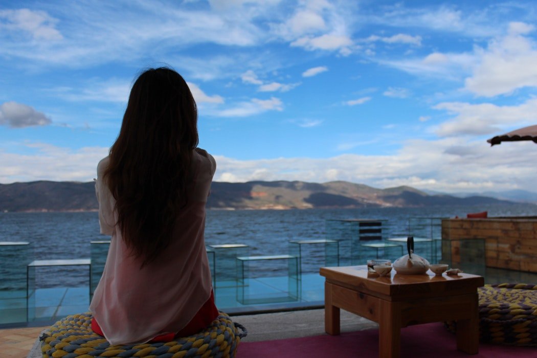 Menina sentada em varanda em frente ao mar