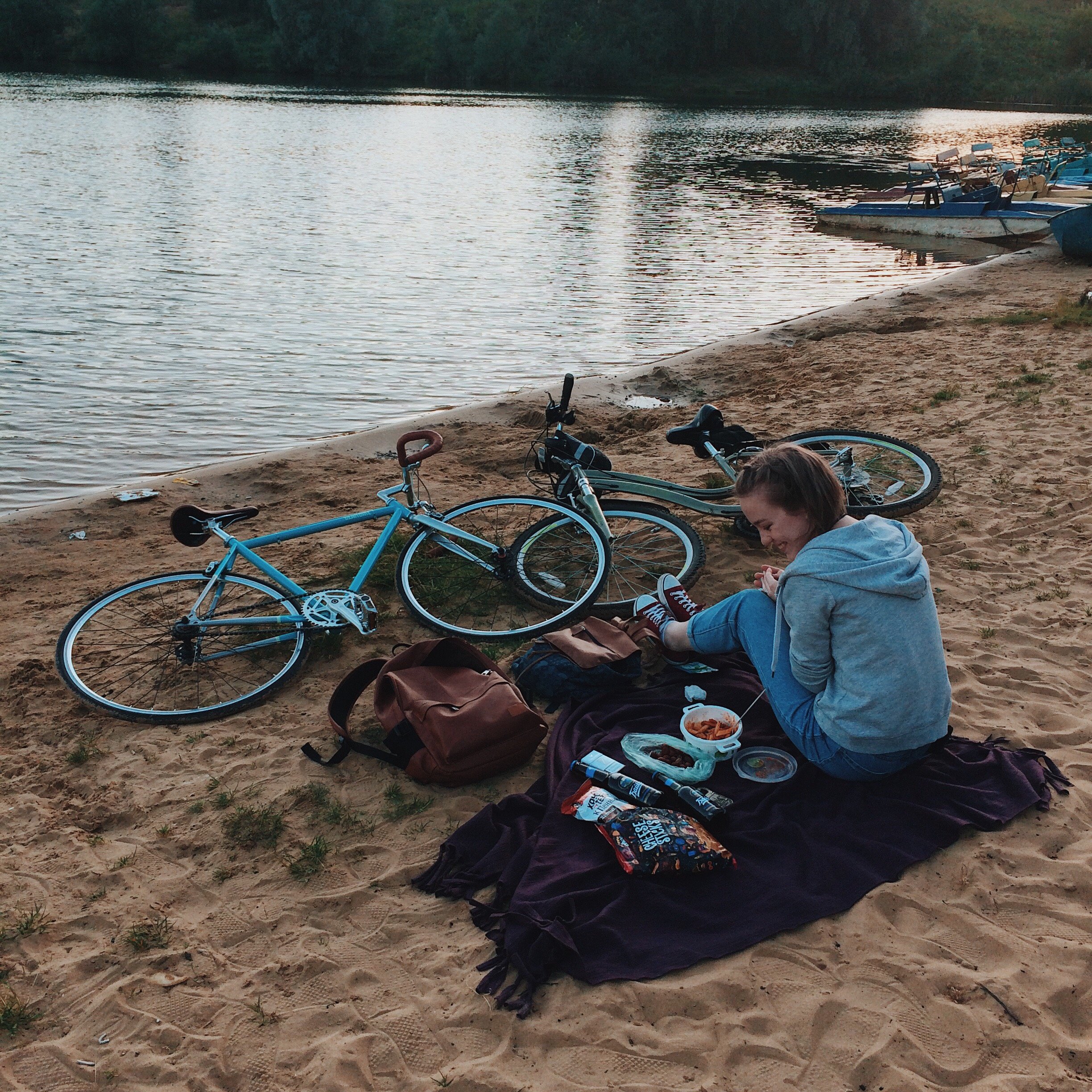 Mulher sentada em uma toalha na areia com duas bicicletas a sua frente