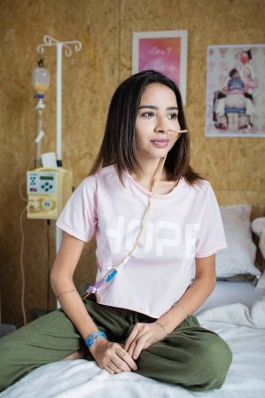 Nara Almeida sentada em cama olhando para o lado