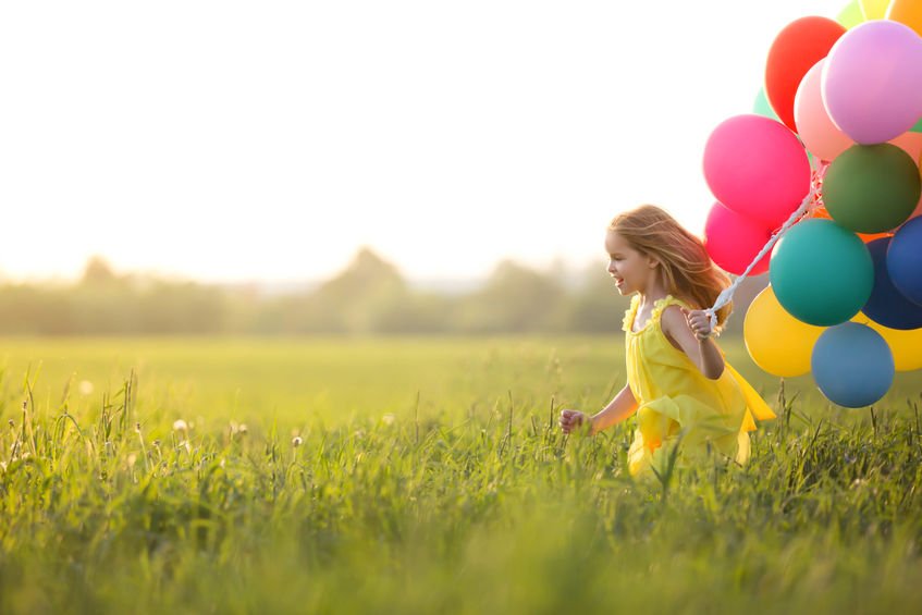 Criança correndo com balões