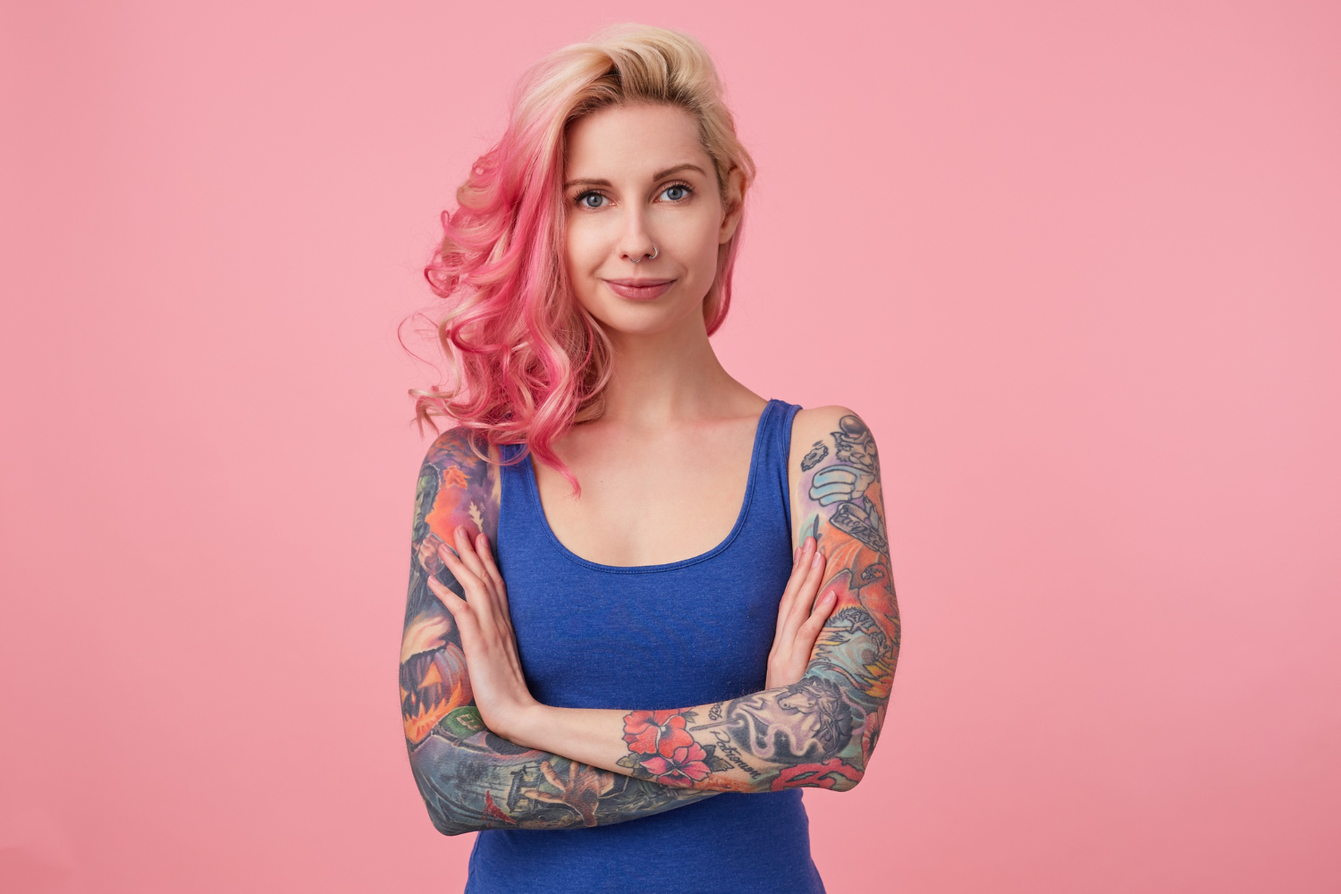 Mulher branca, com cabelo louro e rosa, com braços tatuados
