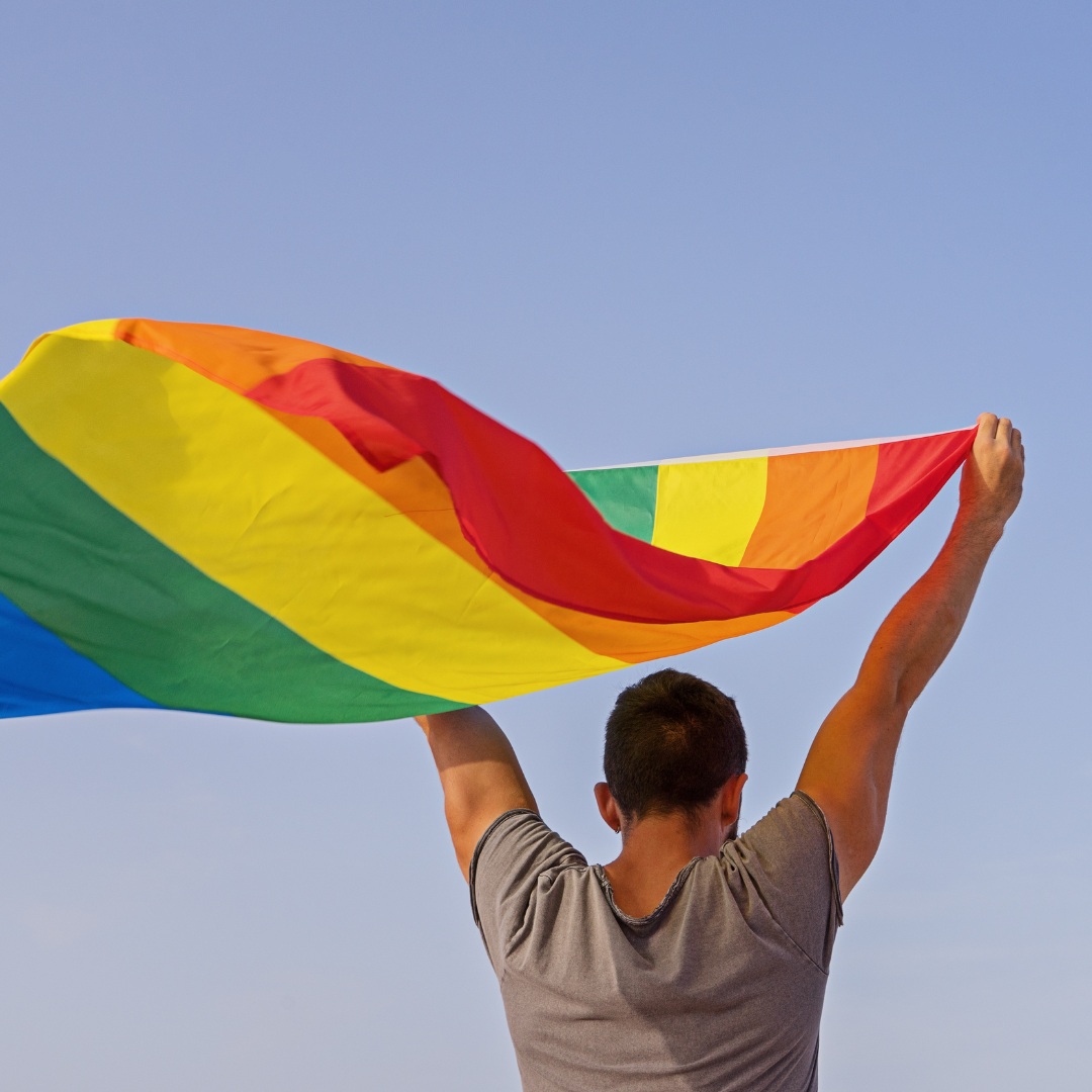 Homem branco levantando bandeira LGBT.