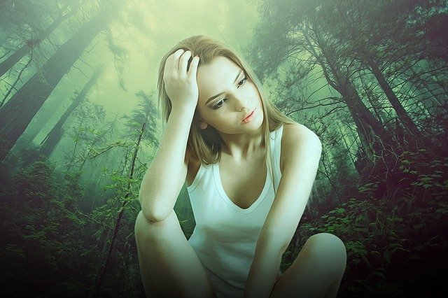 Menina triste sentada em floresta